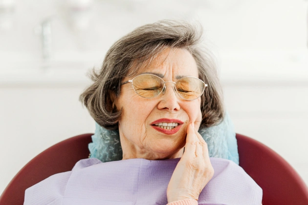 Senior woman with hand to face smiling in dental office setting