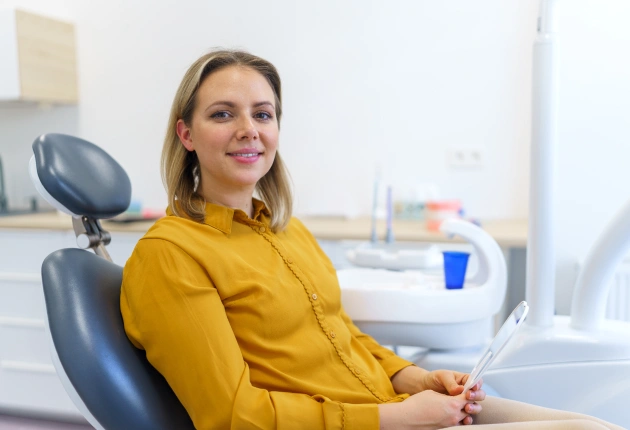 Woman in yellow shirt sitting in dental chair at professional dental office.