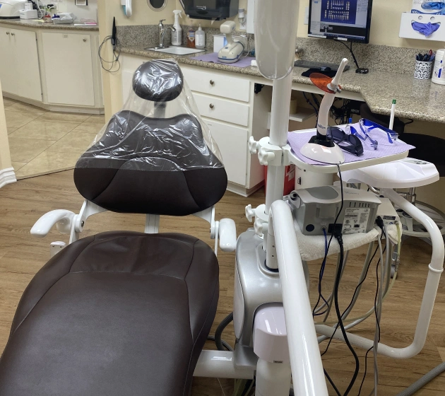 Dental examination chair with overhead light and equipment in modern dental office operatory.