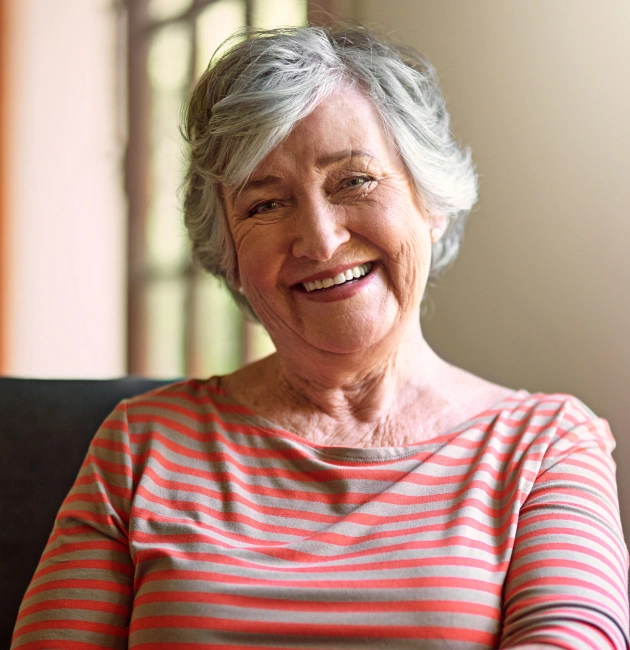 Smiling senior woman wearing striped shirt in indoor home setting