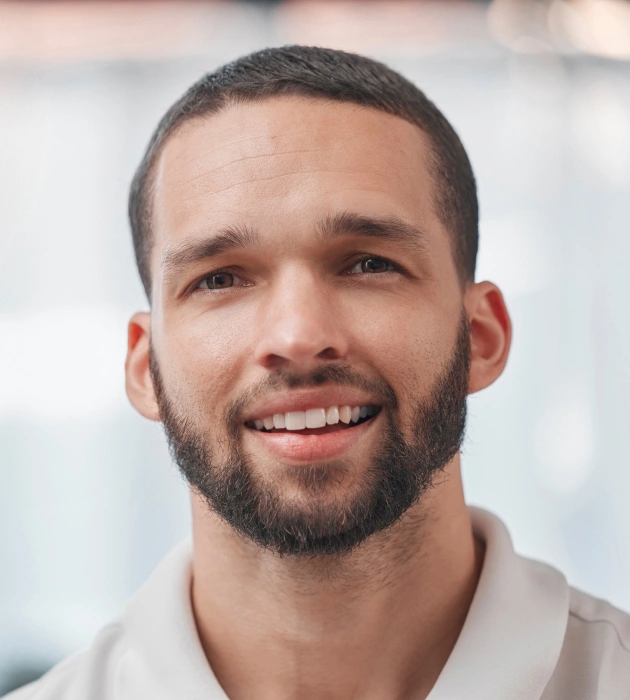 Professional headshot of smiling male dental care provider in clinical setting