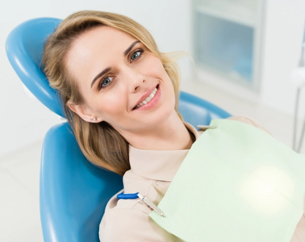 Woman in dental chair holding mirror, smiling at Escondido Family Dental Care office