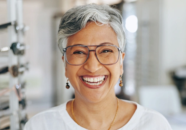 Smiling female optometrist wearing glasses in modern eyewear clinic setting.