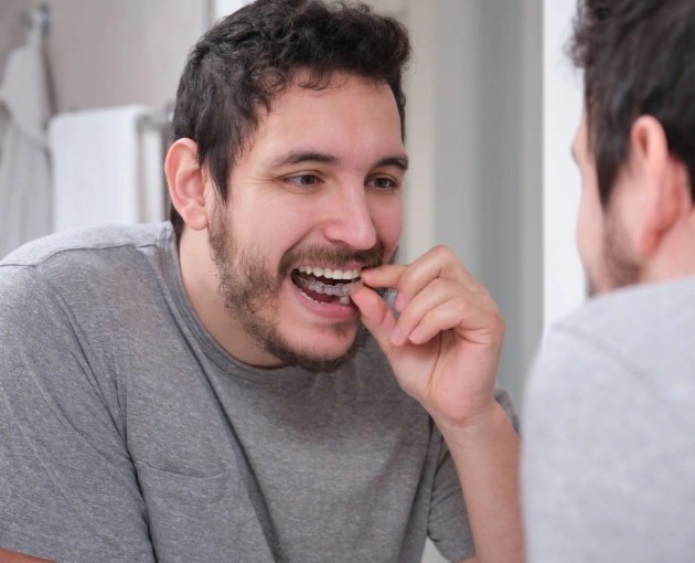Man brushing teeth at bathroom mirror in casual gray shirt