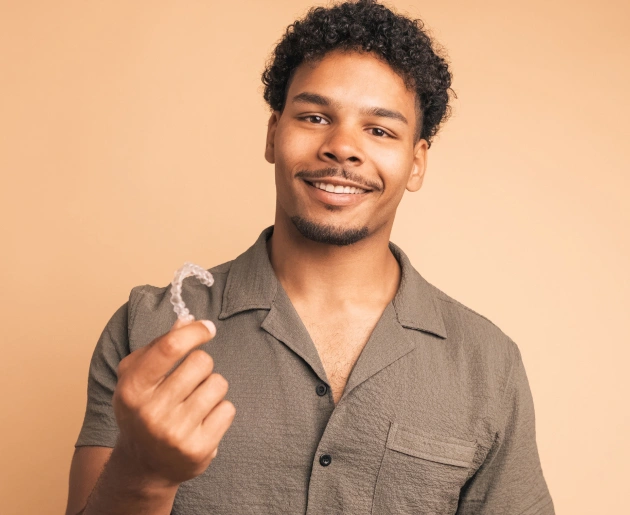 Smiling man in brown shirt making beckoning gesture against beige background