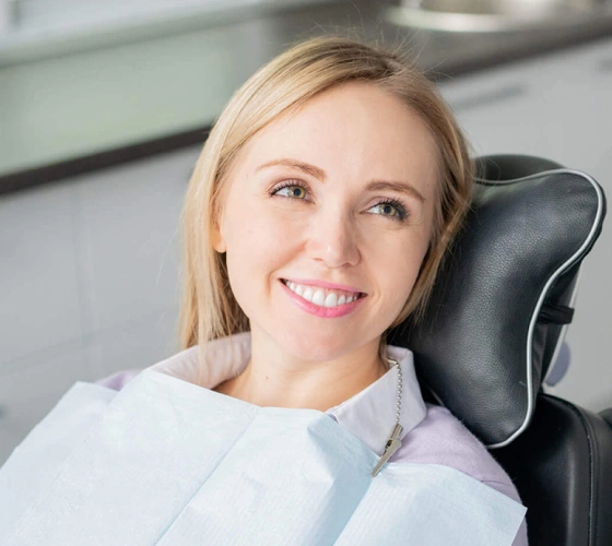 Smiling woman in dental chair wearing light blue shirt at professional dental office