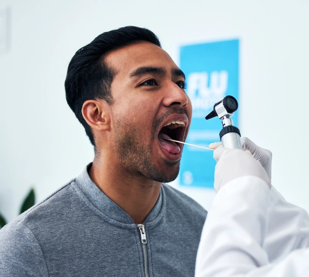 Man receiving dental examination or treatment at dental office with blue signage visible.