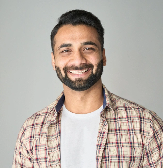 Smiling male dental professional in plaid shirt against neutral background at Escondido Family Dental Care.