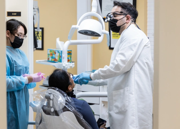 Dentist and assistant examining patient in modern dental office with overhead light.