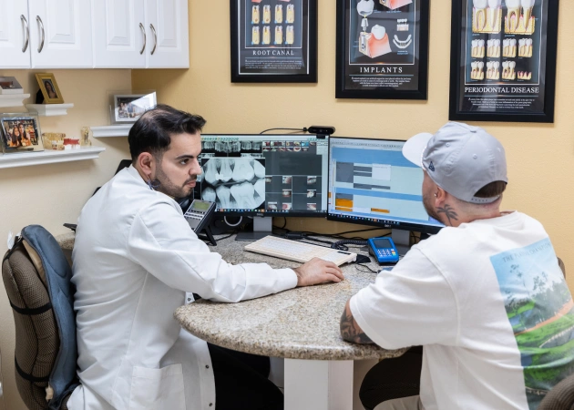 Two dental professionals review patient records at computer workstation in modern dental office.
